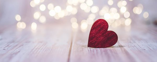 Close up of red heart on wooden table against defocused bokeh light background. Love, valentine's day concept.